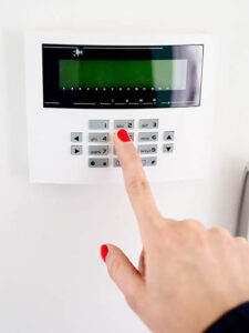 Young woman entering security code on home security alarm system keypad